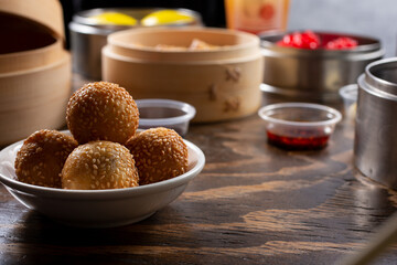 A view of sesame balls among other dumplings in steamer containers.