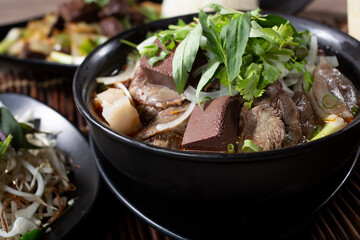 A closeup view of a bowl of bun bo hue Vietnamese soup.