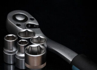 Ratchet wrench. Set of stainless steel hex sockets on shiny black surface. Universal professional...
