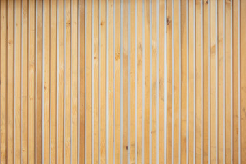 A view of a vertical thin planks of wood as a wall facade and background.