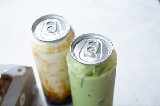 A view of two novelty boba milk tea aluminum can tops on plastic bottles.