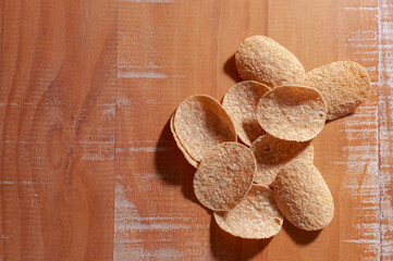 Top view of some potato chips on a wooden table.