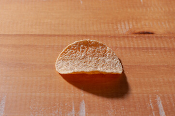 Close-up of a potato chip on a wooden table.