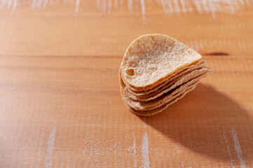 Close-up of a pile of potato chips on a wooden table. 
