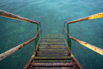 Rusty iron stairs into the blue sea