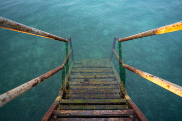 Fototapeta premium Rusty iron stairs into the blue sea