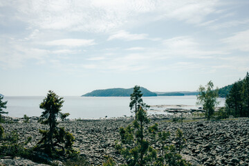 Cobblestone beach, blue sky and still waters on the high coast hiking trail, Sweden. Slightly toned down colors and adjusted to turquoise tone. 