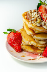 Pancakes stacked with bananas, strawberries and nuts, topped with chocolate and strawberry sauce