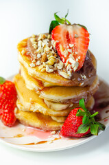 Pancakes stacked with bananas, strawberries and nuts, topped with chocolate and strawberry sauce