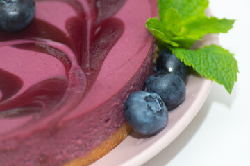 Closeup to baked vanilla and berries flavour cheesecake swirled with blueberry sauce on a digestive biscuit crumb