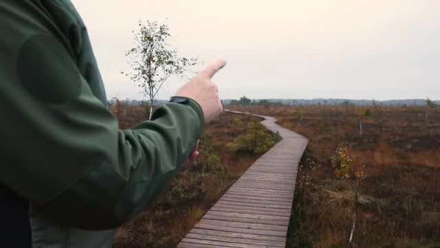 Unrecognizable man in wilderness surrounding is trying to determine his location using a mobile compass  app on his smartphone. Lost in willdernerss concept. 