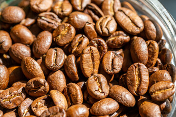 Roasted coffee beans in a glass jar closeup. Morning sunlight