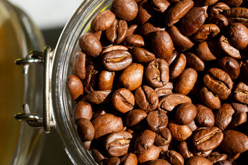 Roasted coffee beans in a glass jar closeup. Morning sunlight
