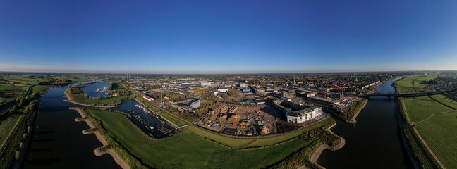 Obraz premium Construction site PUUR21 aerial with wide view of Noorderhaven neighbourhood along the river IJssel against a clear blue sky. Urban development in tower town Zutphen, The Netherlands.