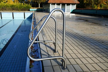 Schwimmbad Panorama mit Schwimmbecken ohne Wasser, Geländer am Beckenrand und Wärmehalle am...