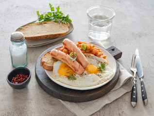 Traditional English breakfast with fried eggs, sausages, beans, fresh herb, red pepper and toast on a gray background. Concept morning food