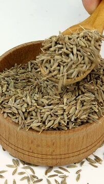 Chef taking chopped dry cumin seeds or zira spices from wooden spice jar. Close-up.