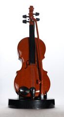Toy violin and bow on a stand facing front in high key