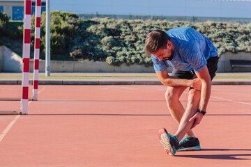 Adult caucasic man 30s, stretching his leg muscles before starting his morning workout outdoors, sport, fitness and wellness concept.