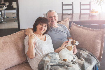 Obraz na płótnie Canvas Happy elderly couple sitting on sofa at home
