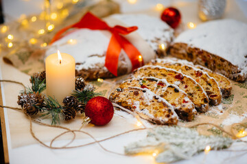 Traditional Christmas stollen made of dried fruits and nuts sprinkled with powdered sugar on the...