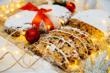 Traditional Christmas stollen made of dried fruits and nuts sprinkled with powdered sugar on the...