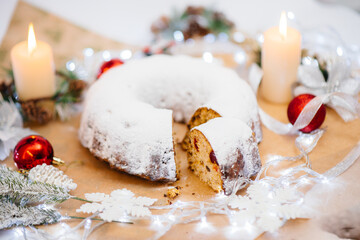 Traditional round Christmas stollen made of dried fruits and nuts sprinkled with powdered sugar on...