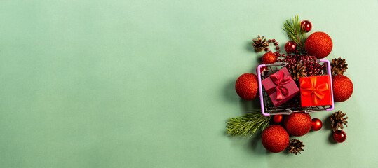 Composition of red gift boxes, Christmas balls, cones and Christmas tree branches on a light green background View with copy space.Flat lay.
