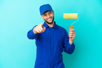 Painter caucasian man isolated on blue background pointing front with happy expression