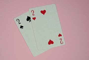 two game cards with deuces lie on a pink table