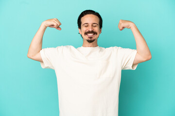 Naklejka premium Young caucasian man isolated on blue background doing strong gesture