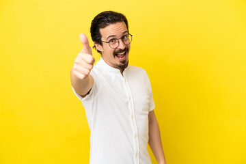 Young caucasian man isolated on yellow background with thumbs up because something good has happened