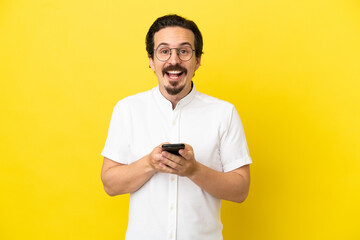 Young caucasian man isolated on yellow background surprised and sending a message