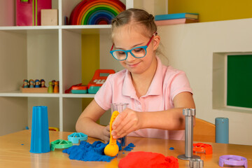 A girl with Down syndrome plays with kinetic sand