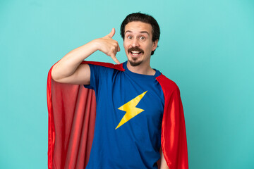 Super Hero caucasian man isolated on blue background making phone gesture. Call me back sign © luismolinero