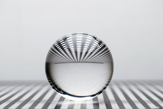 Low angle close up image of a glass toy sphere on a square holed black lattice