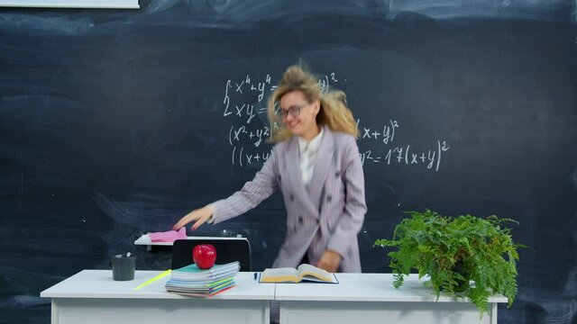 Teacher is happy about beginning or end of school year, vacations. Joyful student found solution to math problem, received highest mark at university. Beautiful girl dancing near blackboard