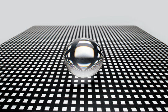 Abstract image of a glass toy sphere on a square holed black lattice