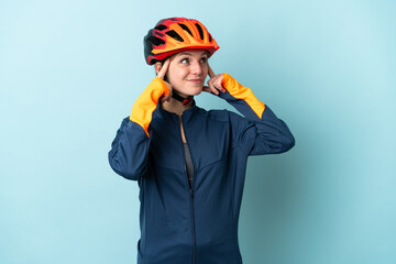 Young cyclist woman isolated on blue background having doubts and thinking