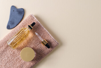 Serum for the care of the skin of the face, eyes, eyelids in a glass bottle on a brown towel,...