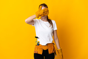 Young electrician woman isolated on yellow background covering eyes by hands. Do not want to see something