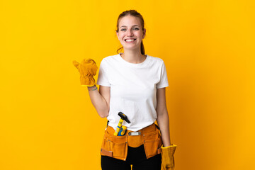 Young electrician woman isolated on yellow background pointing to the side to present a product - obrazy, fototapety, plakaty