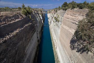 Deep narrow channel cut through the rock with old abandoned bridge
