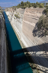 Deep narrow channel cut through the rock with old bridge and shadow of active bridge