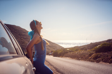 Woman on a road trip arriving with her car by the sea enjoying freedom