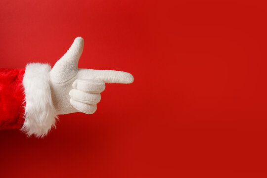 hand of santa claus pointing finger on red background, copy space