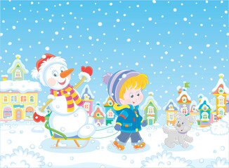 Happy little boy walking with his merry pup and sledding a funny snowman down a snow-covered street of a pretty small town on a beautiful snowy winter day, vector cartoon illustration