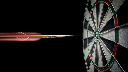 The dart flies into the bullseye dartboard. Blurred dart trail.