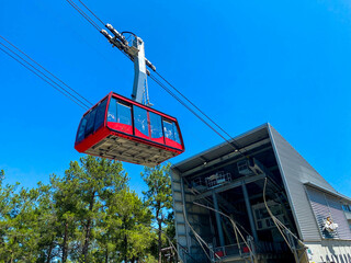 Red modern tourist cabin of the cable car ascends the mountains against the blue sky