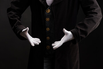 Hand gestures. Show something with your hands, open palms, announcement of the start of the show. Showman or magician illusionist in white gloves on a black background.
